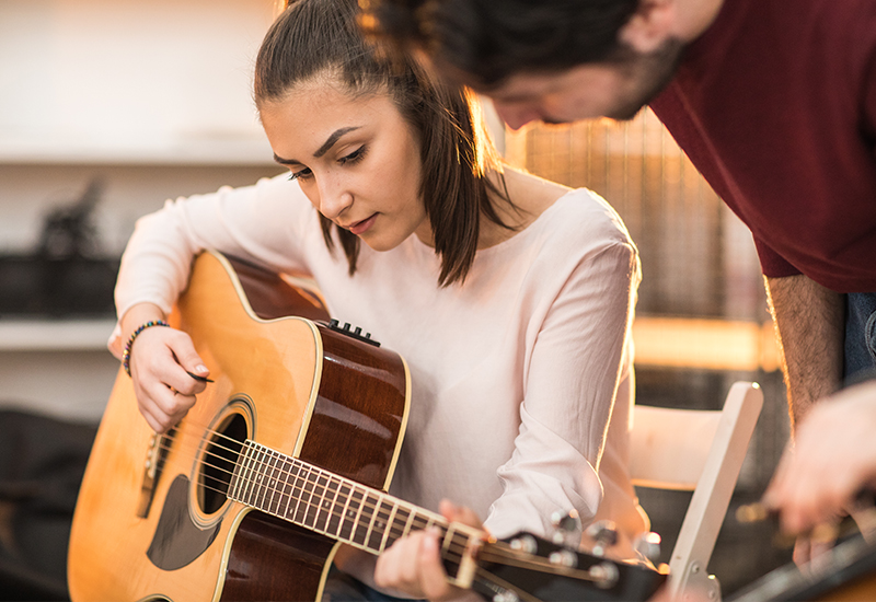 Berufliche Schulen - junge Frau und Lehrer beim Gitarrenunterricht
