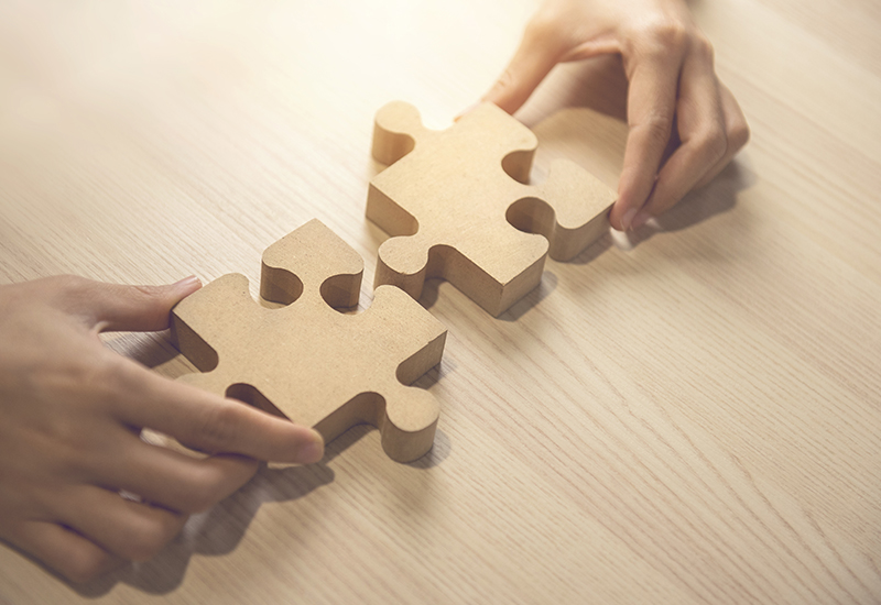 Rahmenkonzepte - Schmuckbild zwei Hände fügen zwei Puzzleteile zusammen